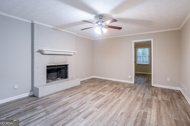 unfurnished living room featuring light wood-type flooring, ceiling fan, a fireplace, crown molding, and a textured ceiling