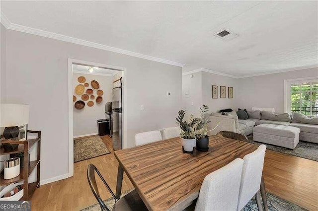 dining space with light wood-type flooring and ornamental molding