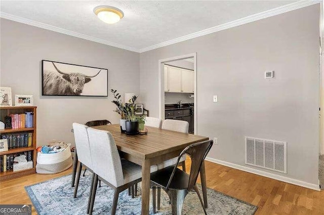 dining area featuring light hardwood / wood-style flooring and ornamental molding