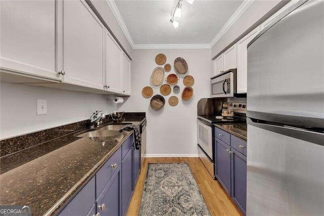 kitchen featuring dark stone counters, blue cabinets, light hardwood / wood-style floors, white cabinetry, and stainless steel appliances