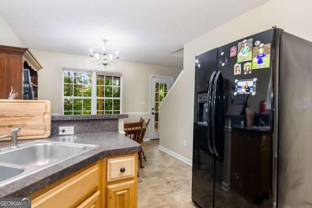 kitchen with black fridge, a notable chandelier, sink, and a textured ceiling