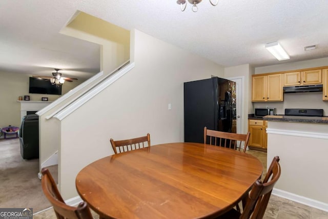 dining area featuring ceiling fan, light colored carpet, and a textured ceiling