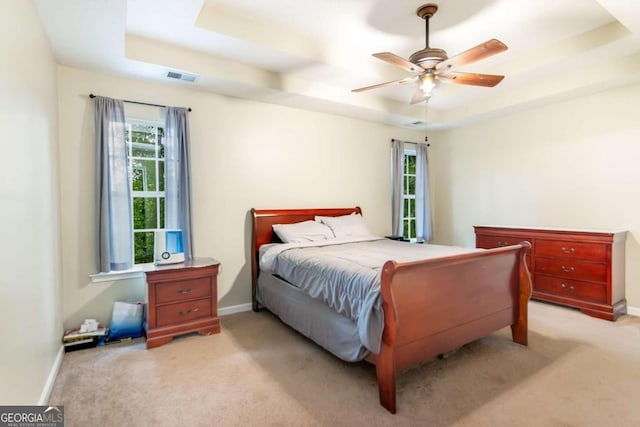 carpeted bedroom with a tray ceiling and ceiling fan