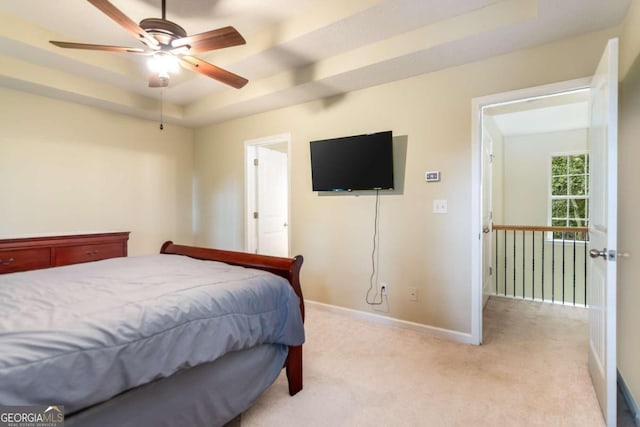 carpeted bedroom with ceiling fan and a raised ceiling