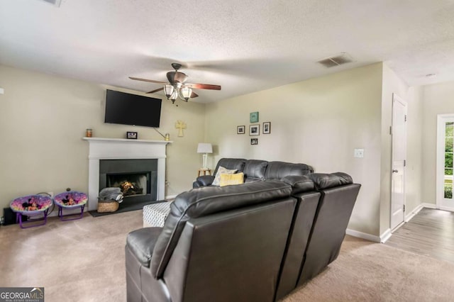 carpeted living room featuring ceiling fan and a textured ceiling