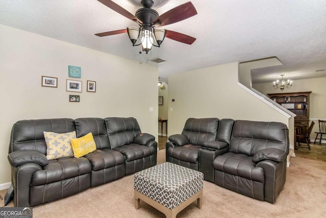 carpeted living room featuring ceiling fan with notable chandelier and a textured ceiling