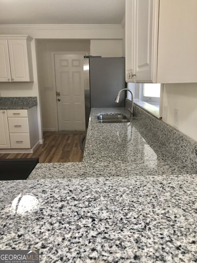 4330 Cedar Valley Ln, Conley, GA 30288 - kitchen with crown molding, light stone counters, wood finished floors, freestanding refrigerator, and white cabinetry