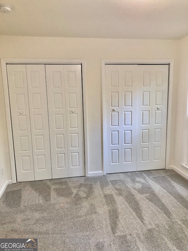 unfurnished bedroom featuring two closets and carpet flooring