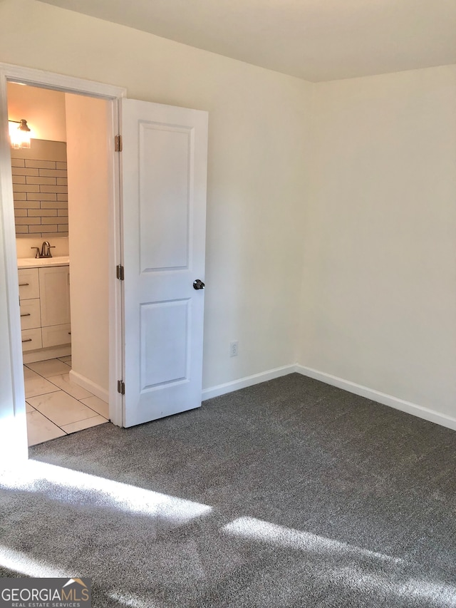 unfurnished bedroom featuring ensuite bath, sink, and carpet