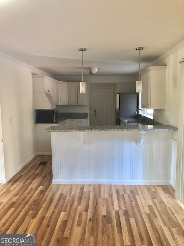 kitchen featuring pendant lighting, kitchen peninsula, fridge, and light wood-type flooring