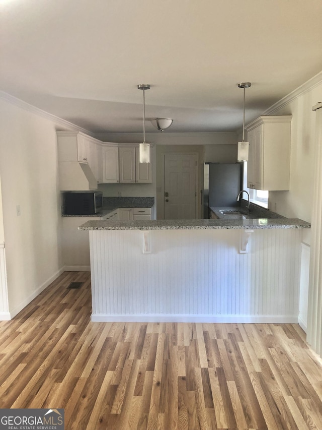 4330 Cedar Valley Ln, Conley, GA 30288 - kitchen with a peninsula, freestanding refrigerator, stone countertops, light wood-style floors, and crown molding