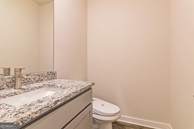 bathroom with hardwood / wood-style flooring, vanity, and toilet