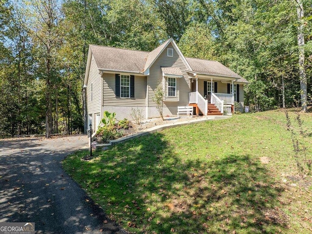 view of front of home featuring a garage, covered porch, and a front yard