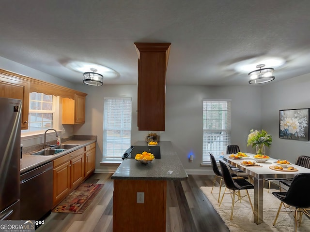 kitchen featuring sink, stainless steel refrigerator, dishwasher, dark hardwood / wood-style floors, and a kitchen island