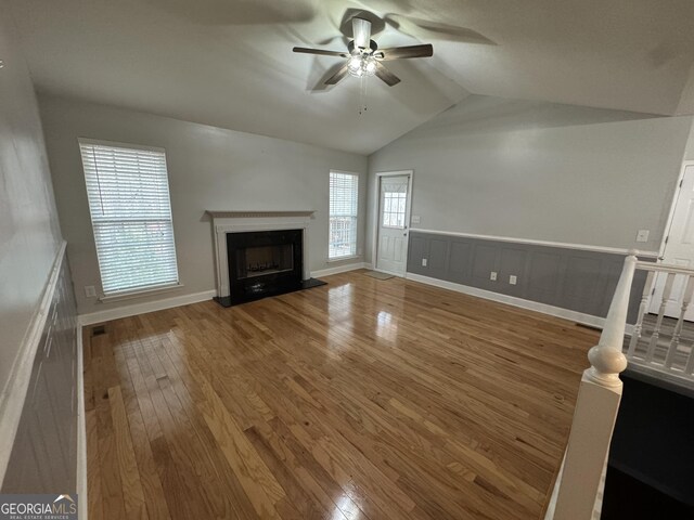 unfurnished living room with hardwood / wood-style floors, vaulted ceiling, and ceiling fan