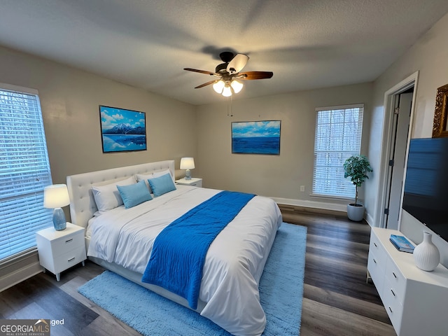 bedroom with ceiling fan, dark wood-type flooring, and a textured ceiling