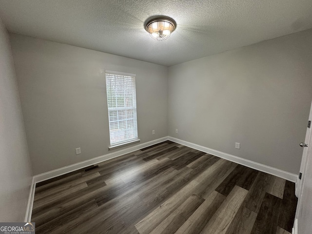 spare room featuring dark hardwood / wood-style floors and a textured ceiling