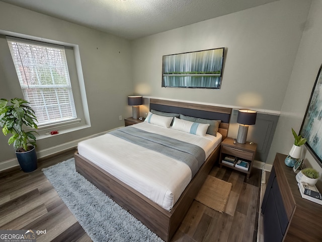 bedroom featuring dark hardwood / wood-style flooring and a textured ceiling