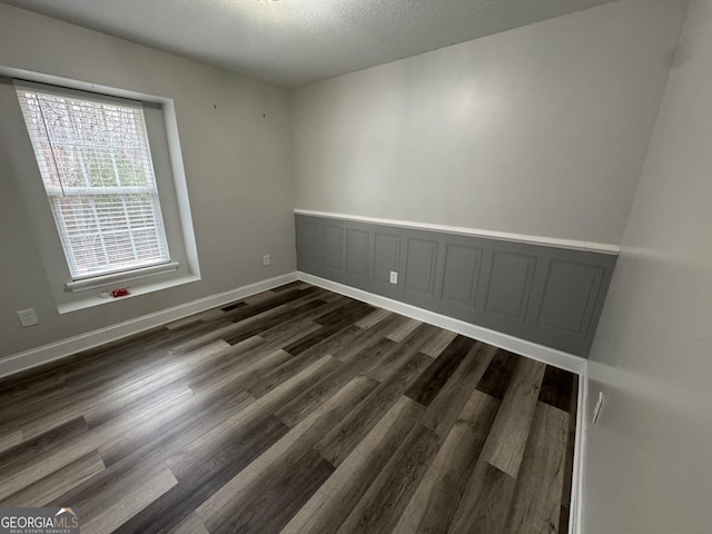 spare room with dark hardwood / wood-style flooring and a textured ceiling