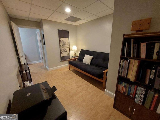 living room featuring light hardwood / wood-style flooring and a paneled ceiling