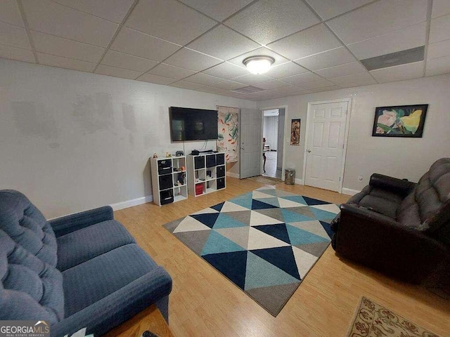 living room with a paneled ceiling and light wood-type flooring