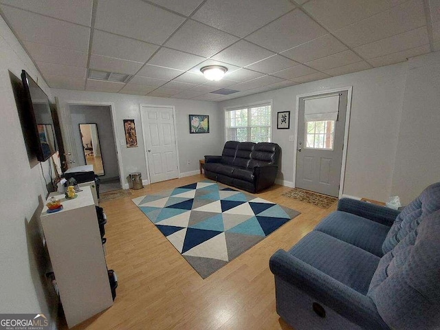 living room with a paneled ceiling and light wood-type flooring