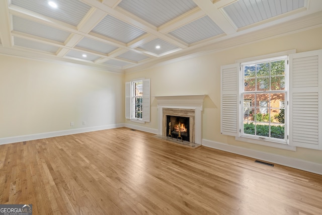 unfurnished living room featuring beamed ceiling, crown molding, coffered ceiling, light wood-type flooring, and a premium fireplace