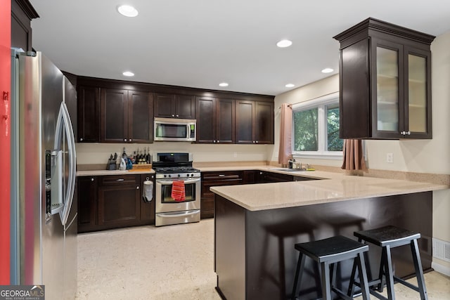 kitchen with sink, stainless steel appliances, kitchen peninsula, and a kitchen breakfast bar