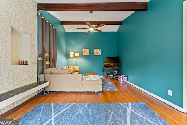 living room with hardwood / wood-style flooring, ceiling fan, and beamed ceiling