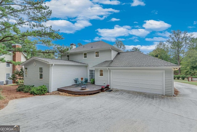 rear view of house featuring central AC unit and a garage