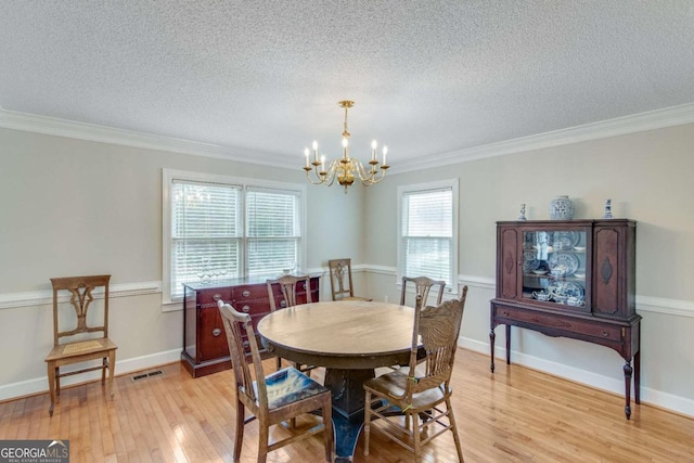 dining area with a notable chandelier, light wood-type flooring, crown molding, and a textured ceiling