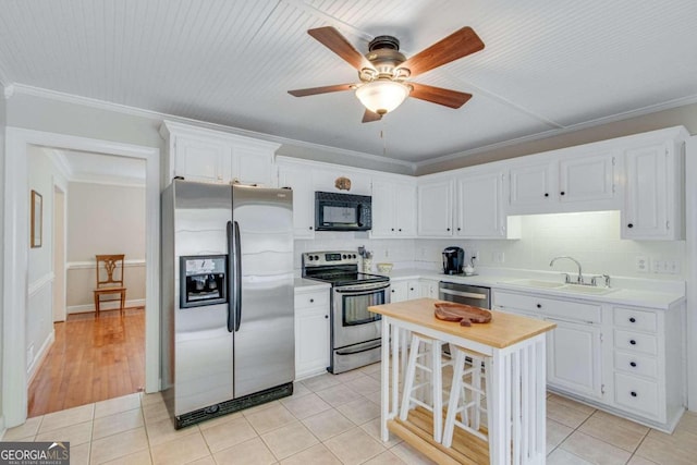 kitchen with white cabinets, ornamental molding, appliances with stainless steel finishes, and sink