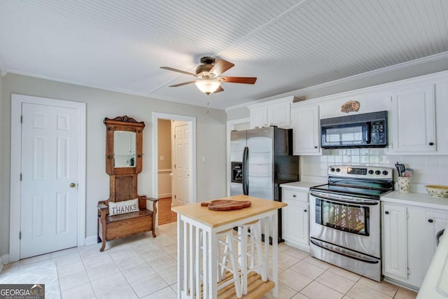 kitchen with stainless steel appliances, decorative backsplash, light tile patterned floors, and white cabinetry