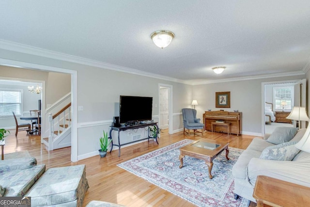 living room featuring an inviting chandelier, hardwood / wood-style flooring, ornamental molding, and a textured ceiling