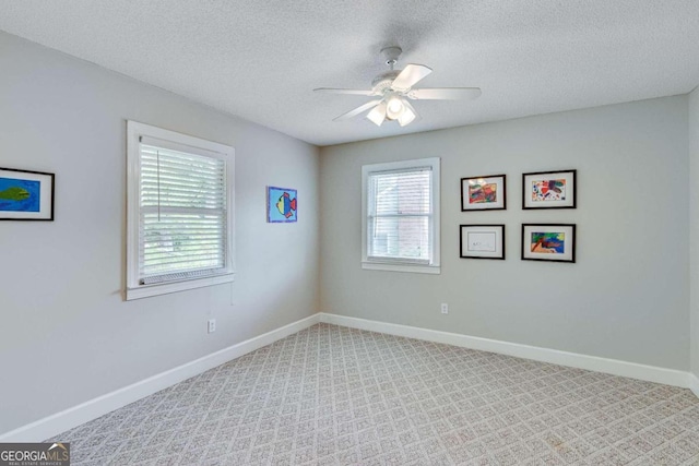 spare room featuring light colored carpet, ceiling fan, and a textured ceiling