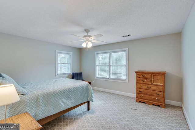 bedroom with ceiling fan, a textured ceiling, and light carpet