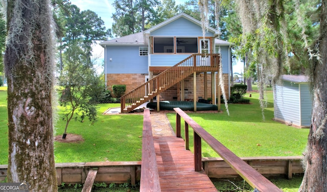 back of house featuring a deck, a yard, and a sunroom