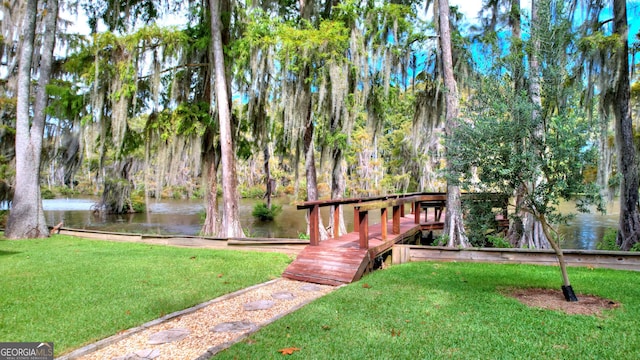 view of home's community with a water view and a lawn