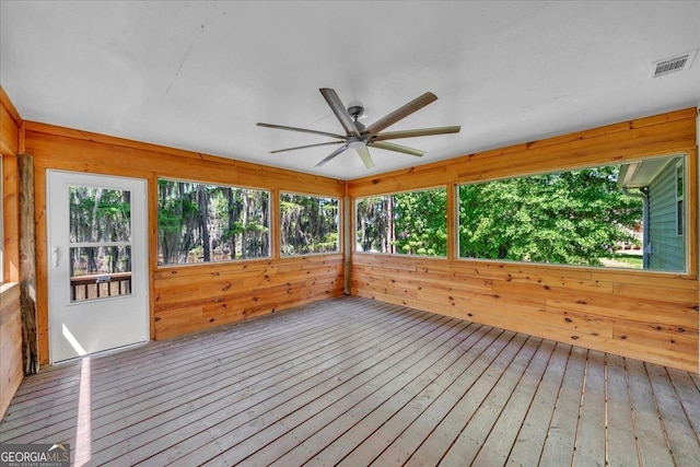 unfurnished sunroom with hardwood / wood-style floors, visible vents, and wood walls