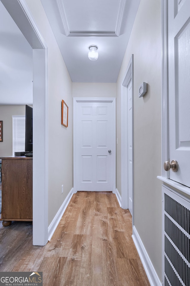 corridor with ornamental molding and light wood-type flooring