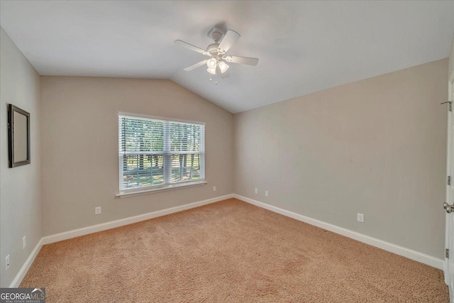 spare room with vaulted ceiling, carpet, a ceiling fan, and baseboards