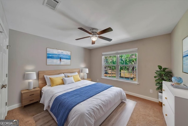 bedroom featuring visible vents, a ceiling fan, baseboards, and light colored carpet