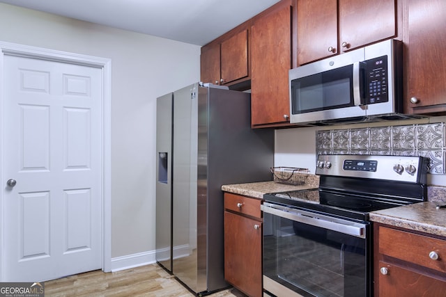 kitchen with appliances with stainless steel finishes and light hardwood / wood-style floors