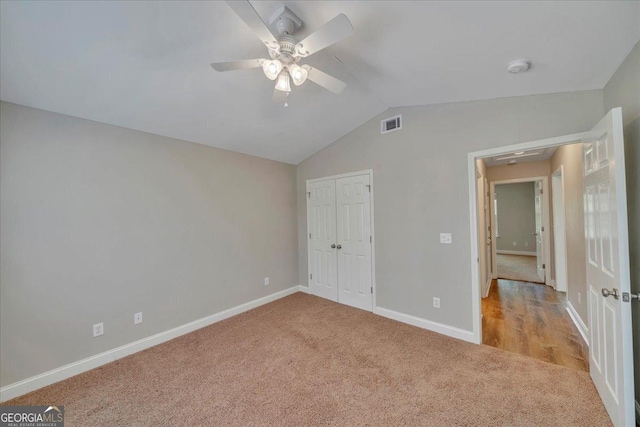 unfurnished bedroom with vaulted ceiling, visible vents, baseboards, a closet, and carpet floors