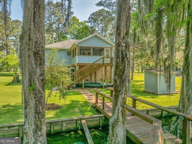 view of playground featuring a lawn, an outdoor structure, a sunroom, and stairs