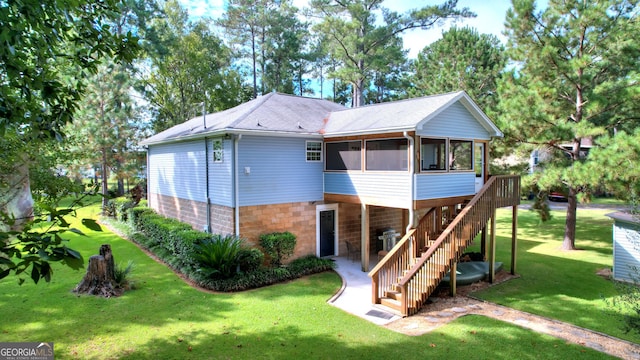 rear view of house with a sunroom and a lawn