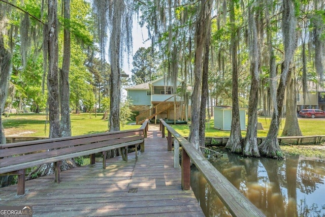dock area with a lawn and a water view