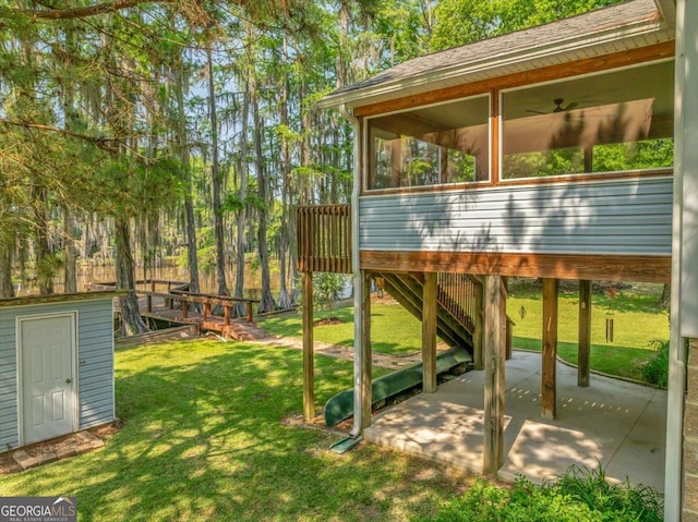 view of yard featuring stairway, a patio area, an outdoor structure, a sunroom, and a storage unit
