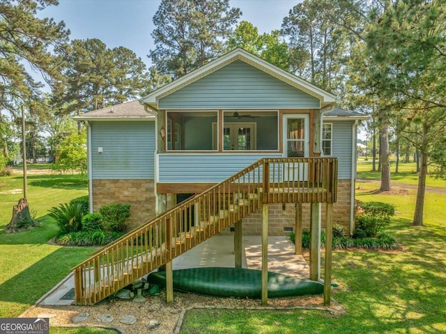 exterior space with stairs, a ceiling fan, a sunroom, and a front lawn