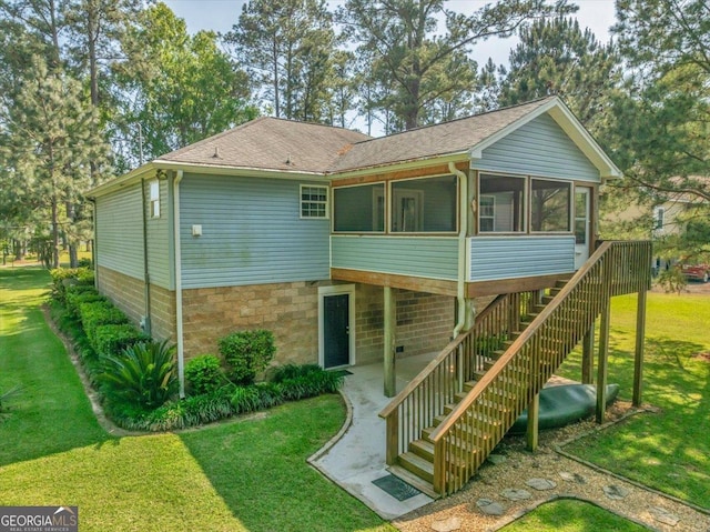 rear view of house featuring a lawn, a shingled roof, a patio, a sunroom, and stairs